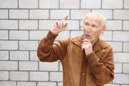 Old man looks with interest on a light background. I have an idea. Old age planningの写真素材