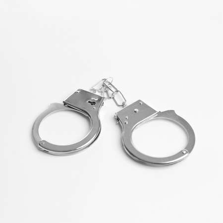 Police handcuffs on a white background. Pair of metal handcuffs macro high resolution close-up.