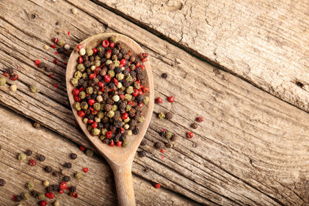 Mix of peppers with peas in a wooden spoon on a wooden background, top view. Red pepper, white pepper and green pepper.の写真素材