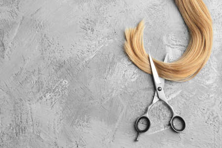 Scissors and piece of blond hair. Professional barber hair cutting shears on background. Hairdresser salon equipment concept, premium hairdressing set. Accessories for haircut with copy spaceの写真素材