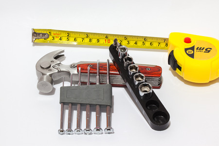 Set of screwdrivers for small screws, tape measure and hammer close-up. Isolated background.