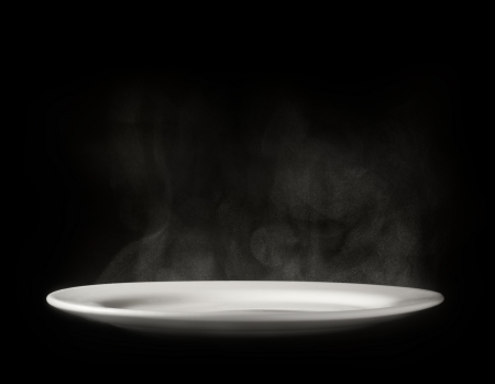 Photo of white plate with steam on black backgroundの写真素材