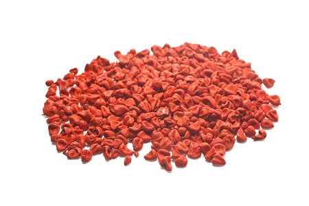 Photo of pile of spices red achiote seeds on white background