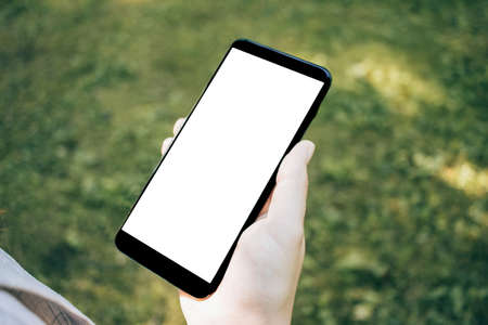Top view mock up image of woman holding smartphone with blank white desktop screen on grass backgroundの写真素材
