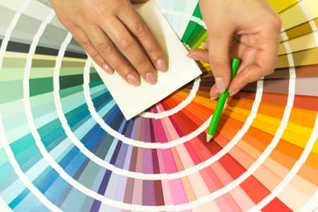 The hand of the designer shows a color palette. Catalog of rainbow color samples.の写真素材