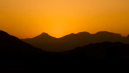 Sunset mountains. Background with orange sky and mountainsの写真素材
