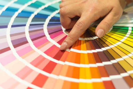 The hand of the designer shows a color palette. Catalog of rainbow color samples.の写真素材