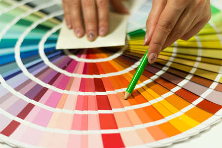 The hand of the designer shows a color palette. Catalog of rainbow color samples.の写真素材