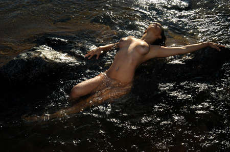 Beautiful naked brunette woman in the riverの写真素材