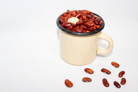 Iron light yellow mug with red and one white beans on white backgroundの写真素材