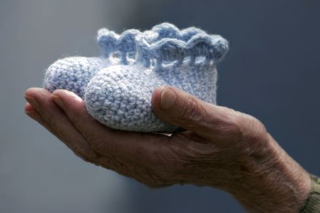 old hand holding baby booties