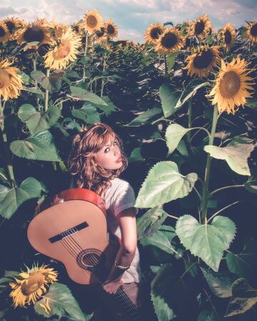 Young girl in a field of sunflowers at sunsetの写真素材