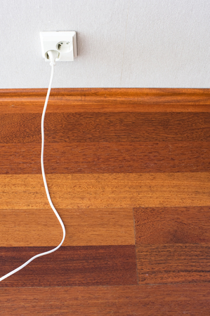 Parquet floor and electric plug connected to the outlet in a wallの写真素材