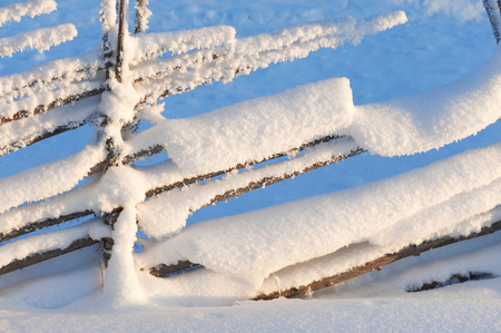 Old wooden fence covered with snow. Winter landscape in Finland.の写真素材