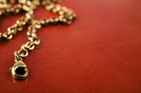 Gold chain on brown background. Focus on foreground, shallow depth of field.の写真素材