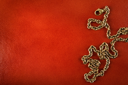 Gold chain on reddish brown leather background.