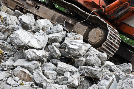 Heavy construction machine above pile of broken concrete at a building demolition site.の写真素材