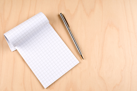 Notepad paper and ballpoint pen on wooden table.の写真素材