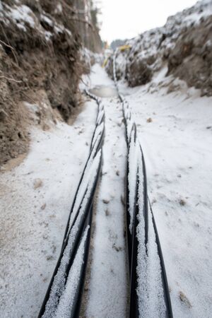 Laying a fiber optic and electricity cables in the frozen ground, buried cables for fast internet in rural region - underground cabling in Finlandの写真素材
