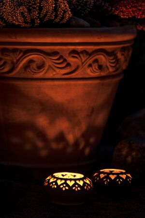 Candle lanterns beside terracotta flowerpot in the gardenの写真素材