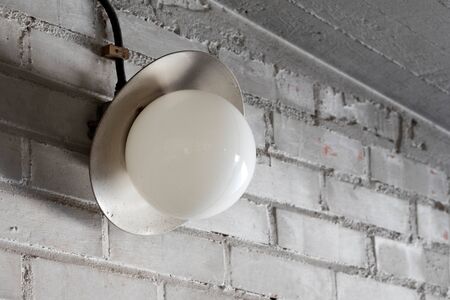 Old electric lamp inÂ the garage brick wall
