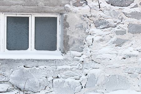 Frost and rime ice covered window and stone wall