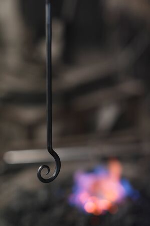 Metal hook made of cast iron, hot forge in the backgroundの写真素材