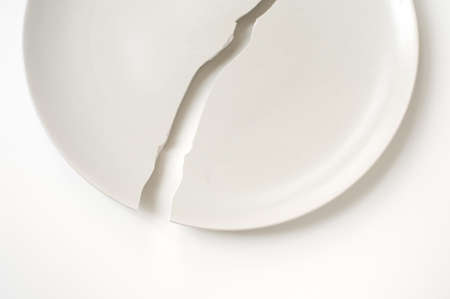 Cracked plate on white table.の写真素材