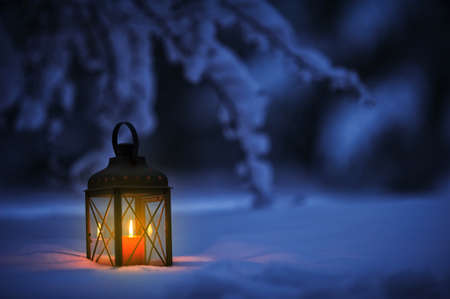 Candle lantern in snow at duskの写真素材