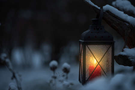 Candle lantern in snow at dusk. Selective focus and shallow depth of field.の写真素材