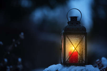 Candle lantern in snow against blurred bokeh backgroundの写真素材