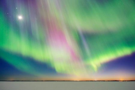 Aurora Borealis and Moon above frozen lake after sunsetの写真素材