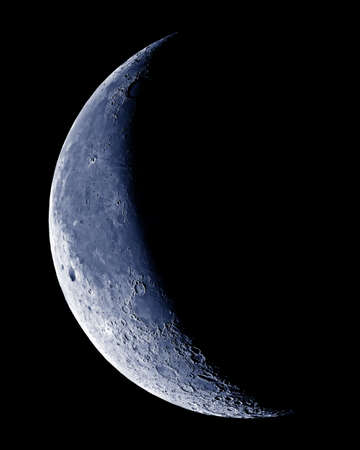 Waning Crescent Moon with crater detail on black sky.の写真素材