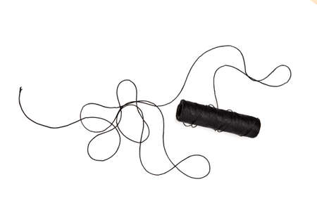 Spool and tangled black thread isolated on white background.の写真素材