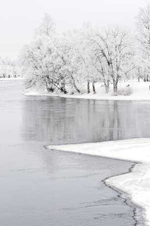 River flowing through winter landscape. Trees covered with frost.