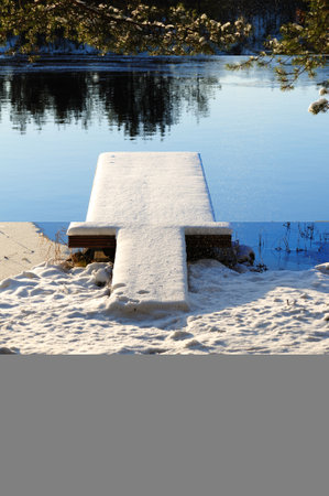 Winter at lake shore, pier covered with fresh snow.の写真素材
