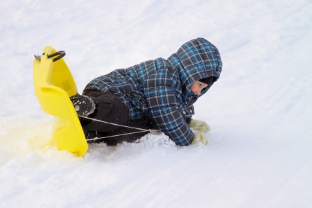Little boy on sleigh - doing an overturn crashの写真素材