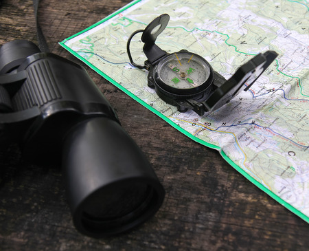 Binoculars and a Compass on the Map in the natural environment during hiking