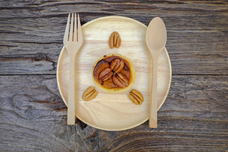 Pumpkin Pecan tart and pine cone on wooden plate with fork and spoonの写真素材