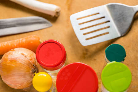 seasonings and cooking utensils on a wood grain cutting board