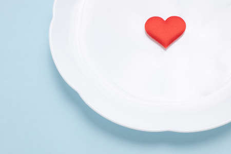 A white dish and a heart-shaped sponge on a blue backgroundの写真素材