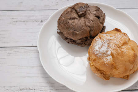 Two kinds of cream puffs on a white plate
