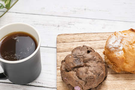 Two types of cream puffs and coffee cups on the cutting board