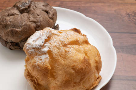 Two kinds of cream puffs on a white plateの写真素材