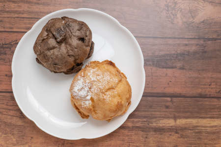 Two kinds of cream puffs on a white plateの写真素材