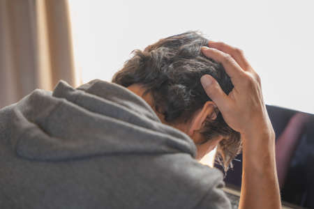 Middle-aged man holding his head in front of a computerの写真素材