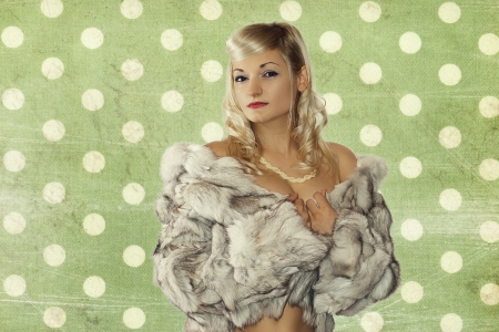 Beautiful girl in a silver fox fur coat from posing on a green background の写真素材