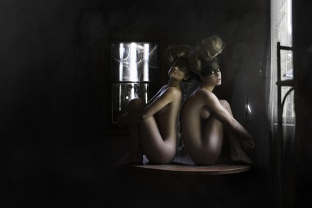 Two girls in the web sit at a desk prislanivshis backs to each other , in an old abandoned house.の写真素材