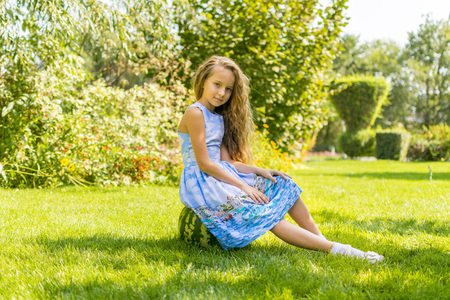 cute little girl eating watermelon on the grass in summertimeの写真素材