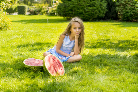 cute little girl eating watermelon on the grass in summertimeの写真素材